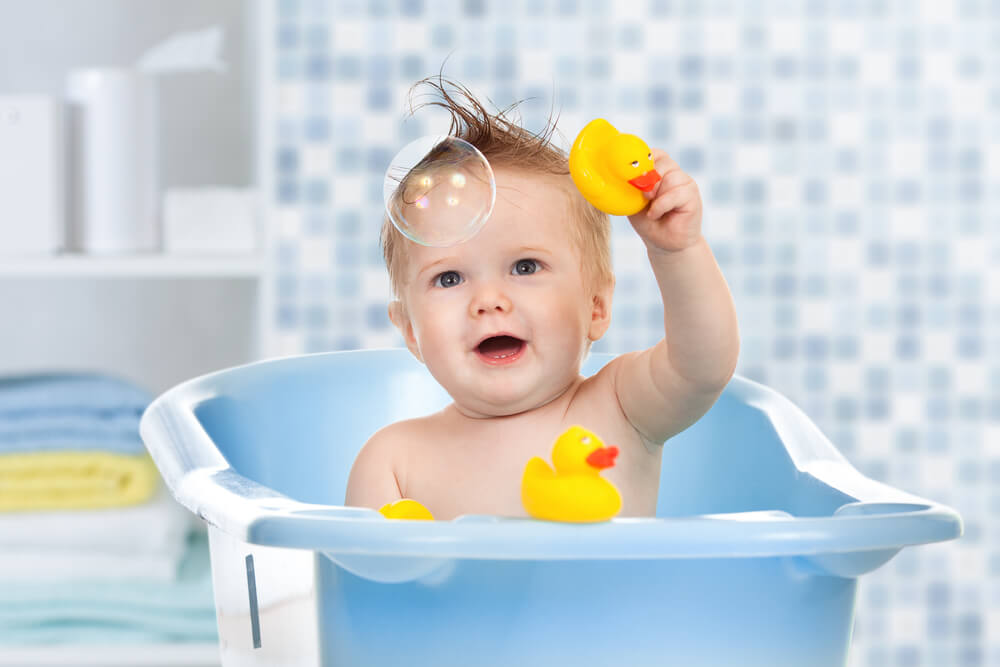 Baby with rubber ducks in bath tub