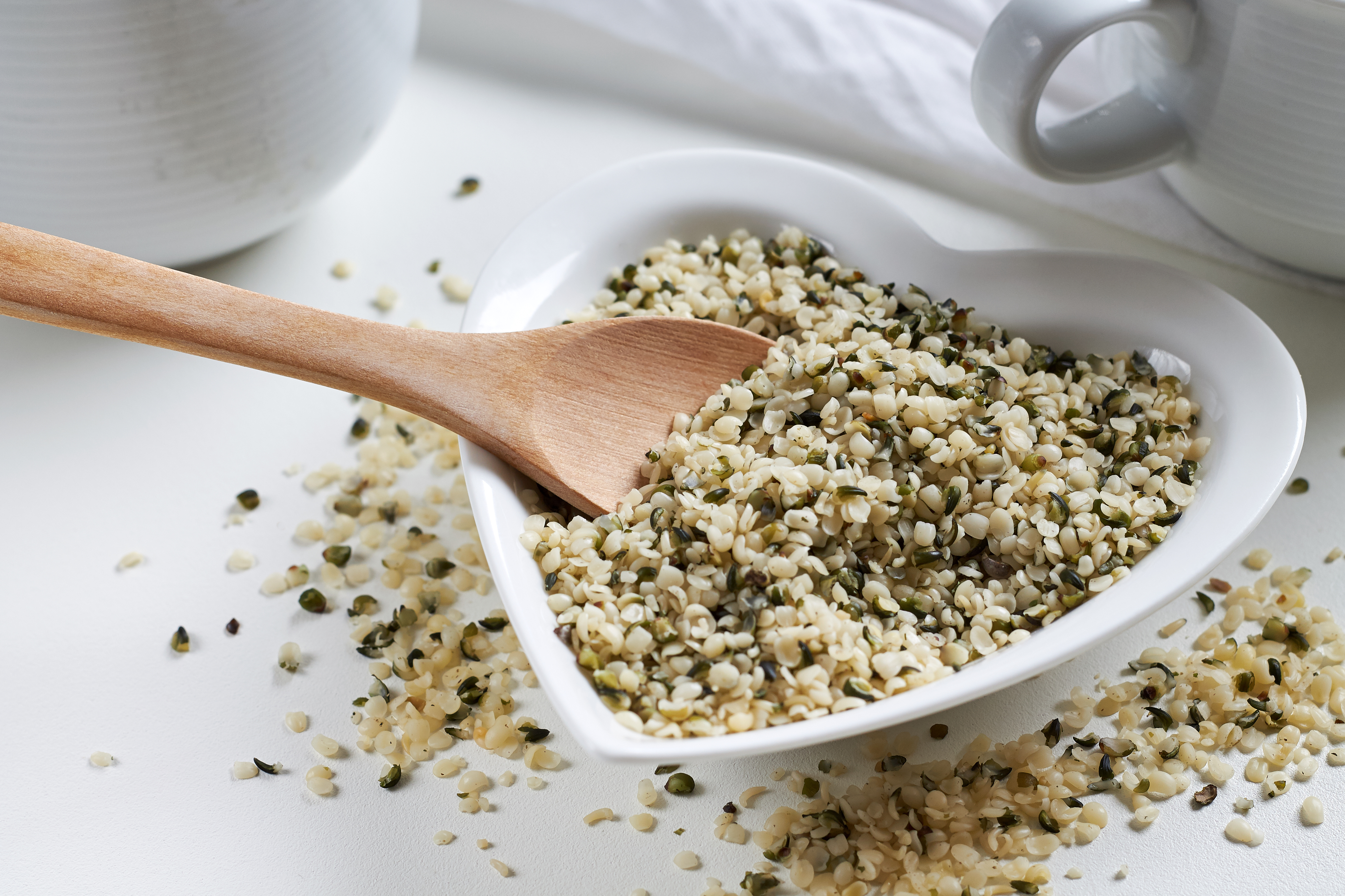 Hemp seeds in heart shaped ceramic bowl and wooden spoon