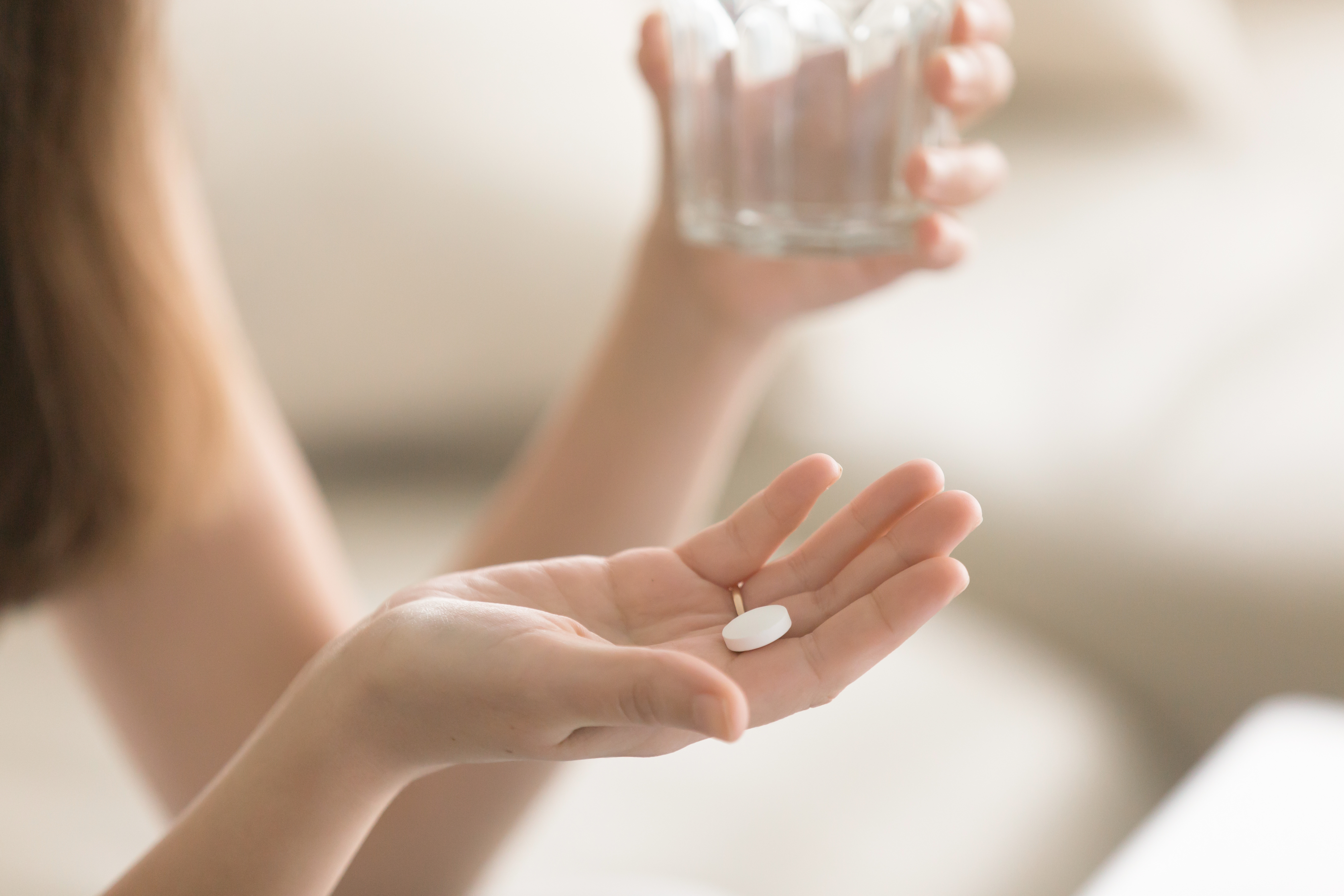 Woman takes magnesium supplement with glass of water