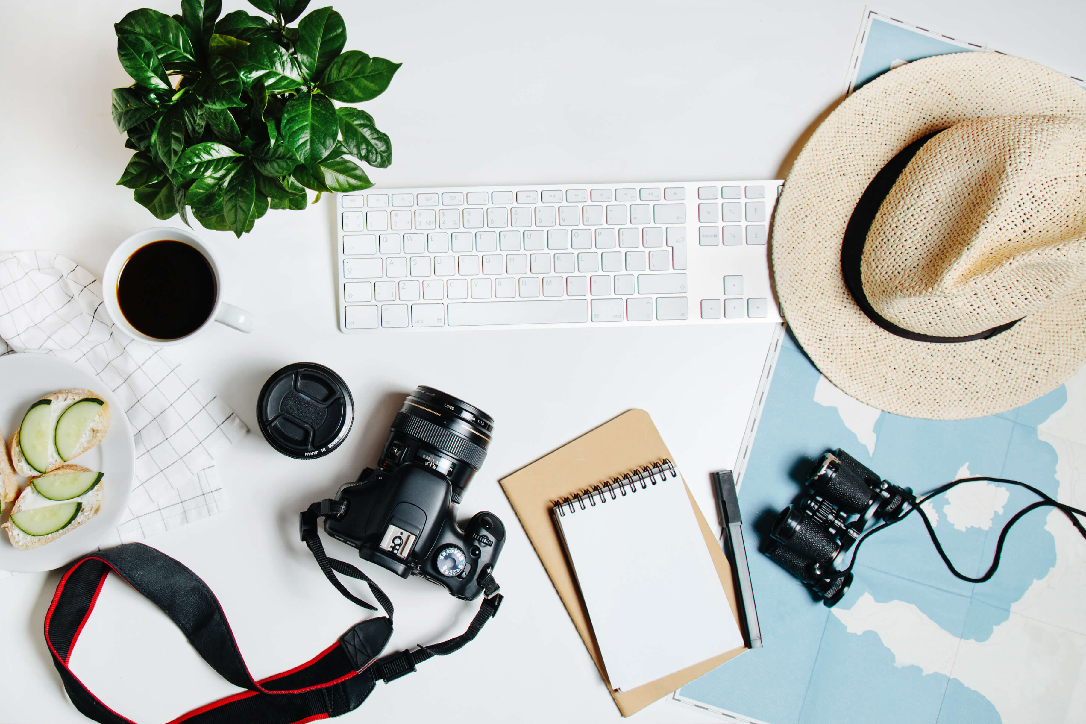 Travel planning flatlay with camera, notebook, sunhat, and more