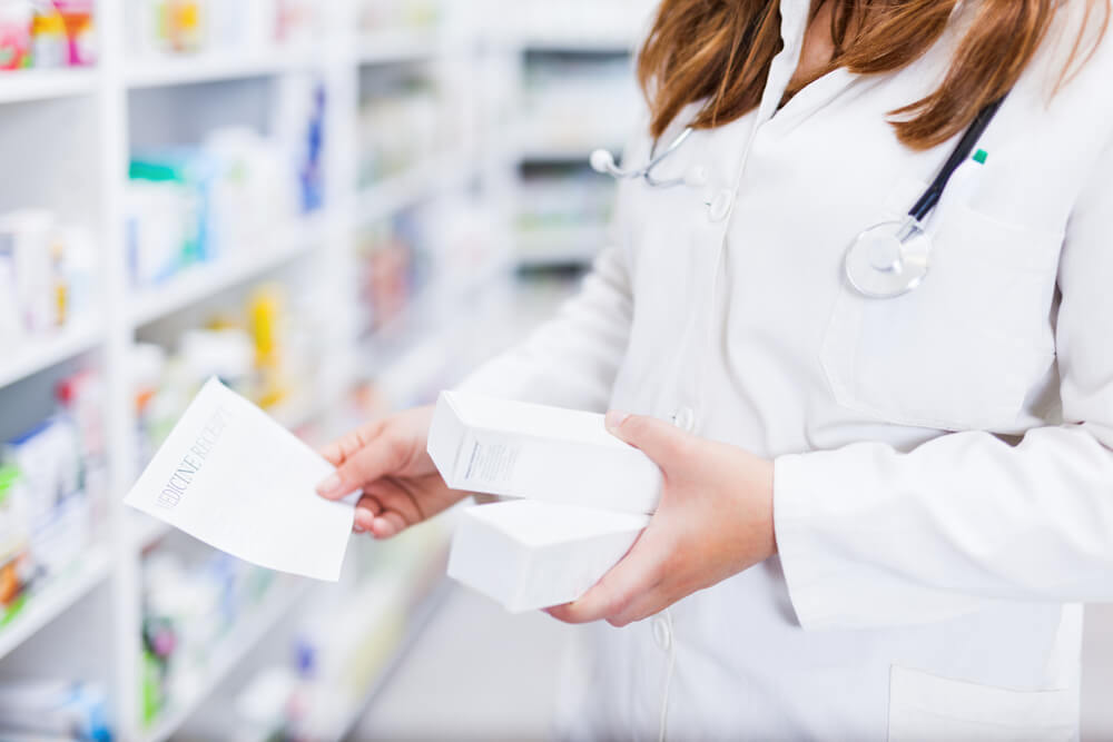 Pharmacist hands holding box container of medicines from shelf close up