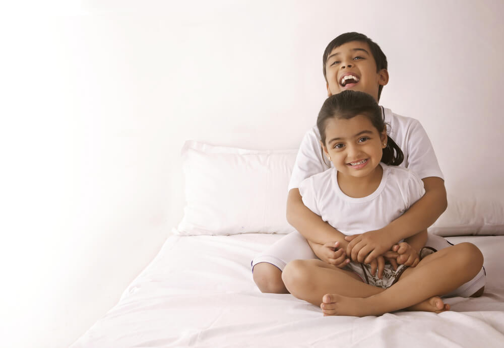 Portrait of happy, healthy girl being embraced by brother
