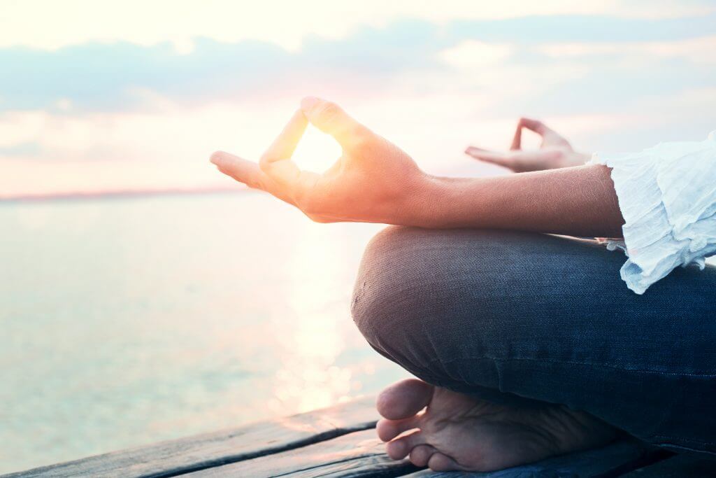 Person meditating by ocean