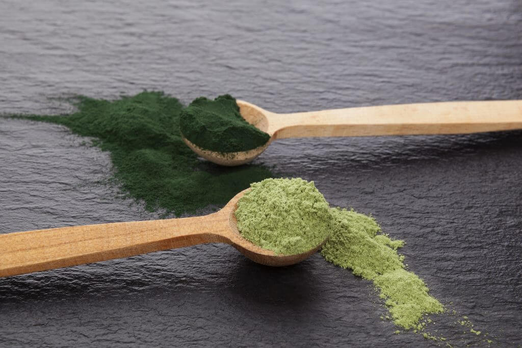 Two spoons with different green powders