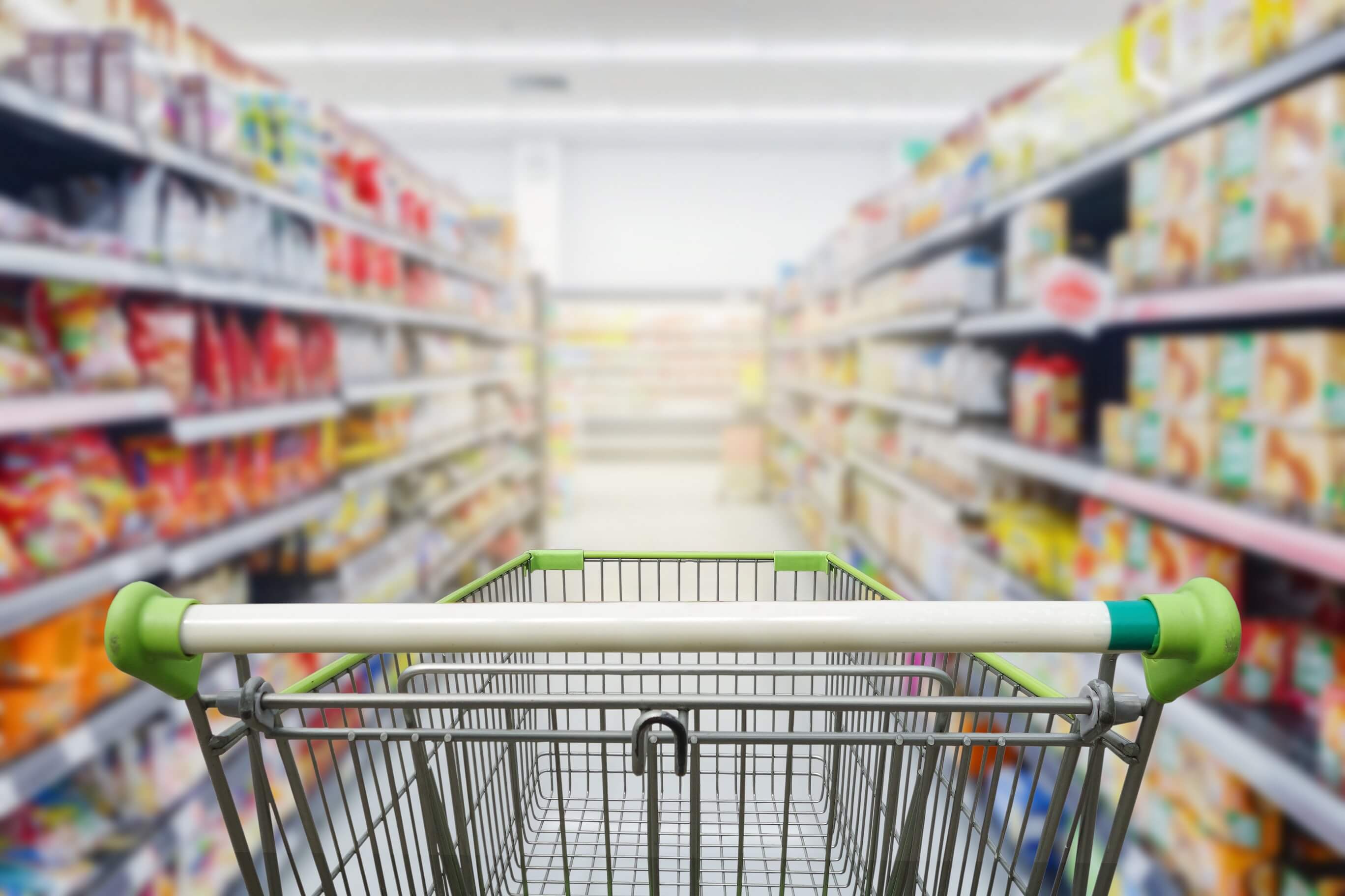 Empty grocery cart in an aisle of processed foods