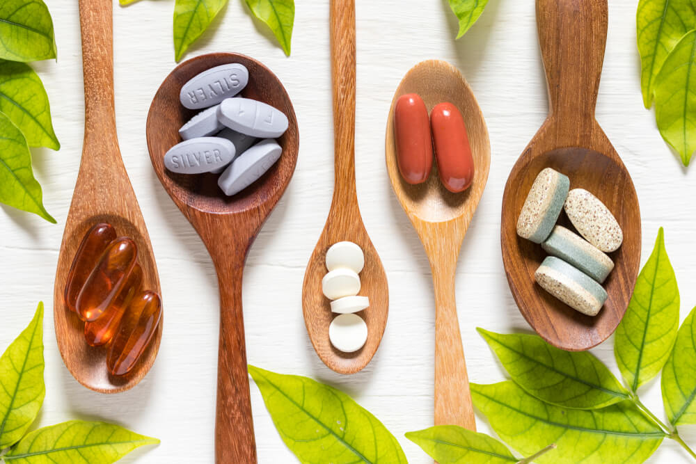 Flat lay of wooden spoons with different colour vitamins