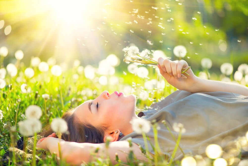 Woman lying in field of dandelions