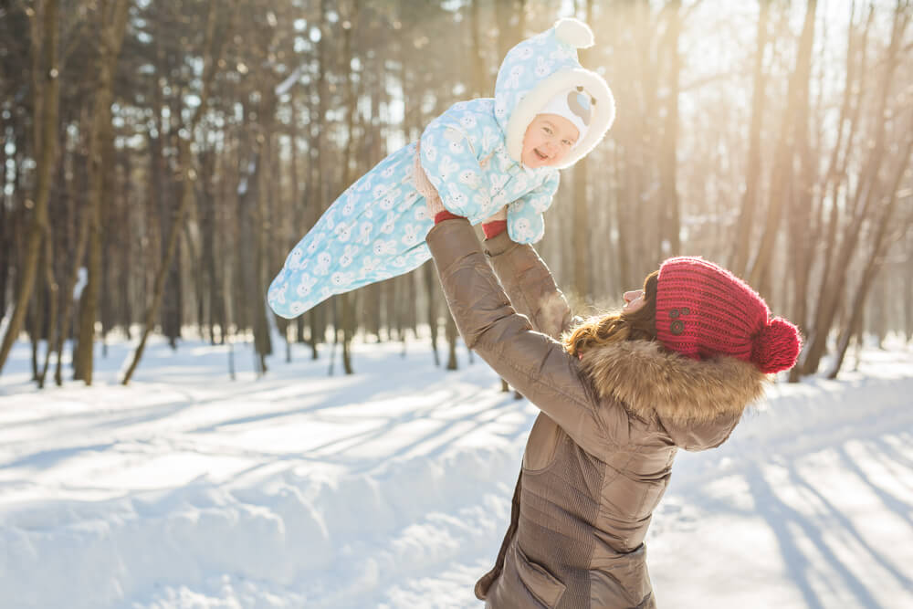 mom holiday baby in the air in the winter
