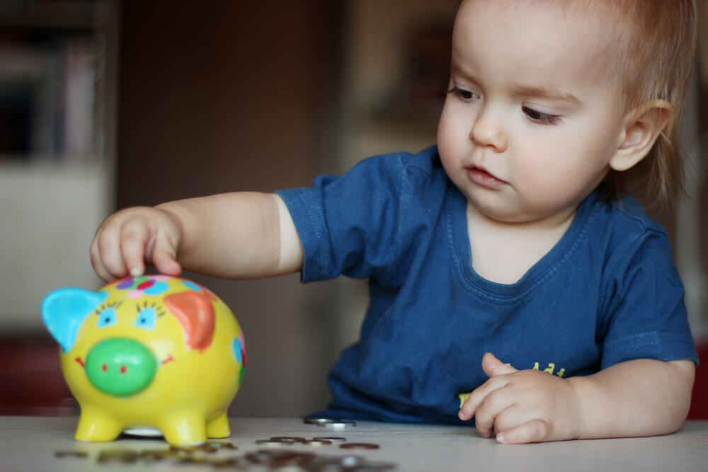 Baby putting coins into piggy bank