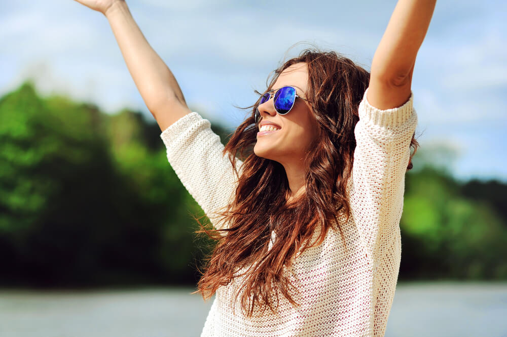 Woman smiling outside with hands in the air