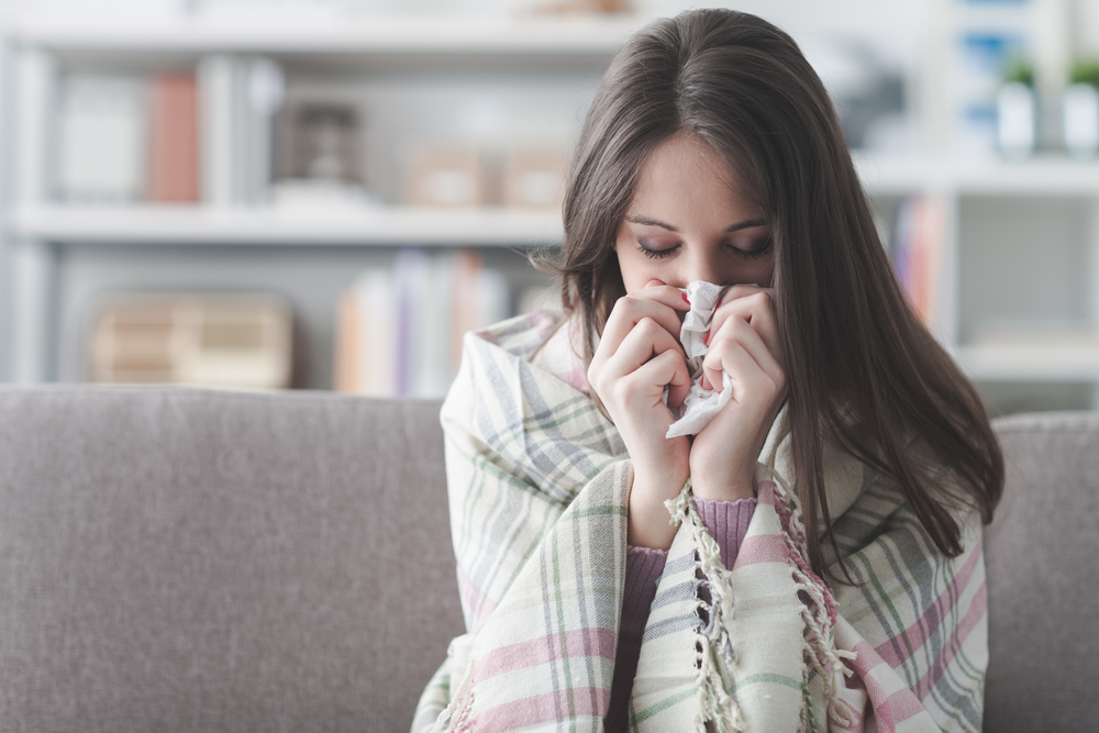 girl sitting on couch blowing nose