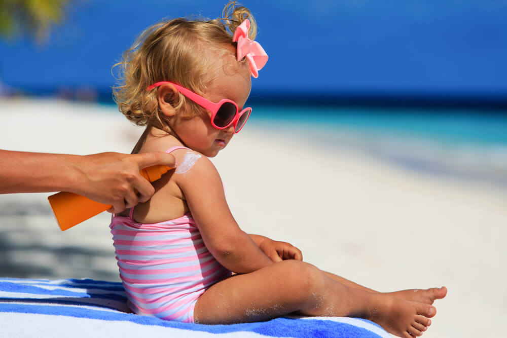 mother applying sunscreen to young girl