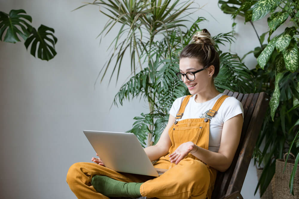 Girl chatting on a laptop with plants in the background