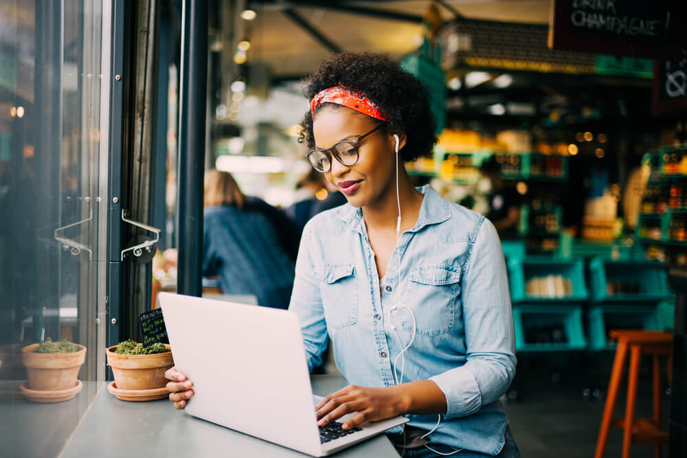 African American woman working on a computer at a coffee shop