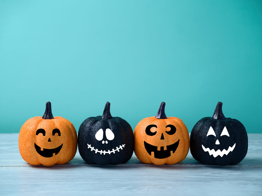 Black and orange mini pumpkin with faces on a blue background