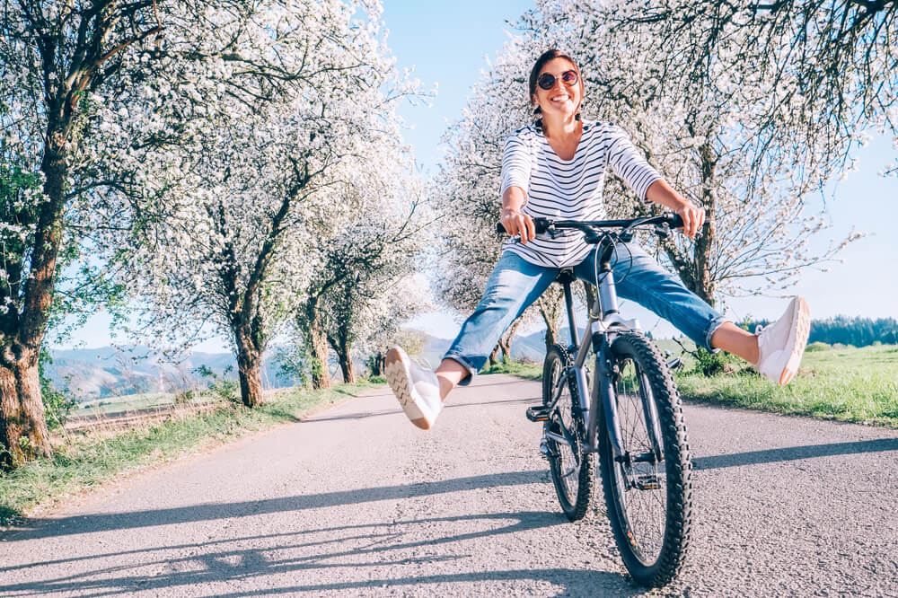 shutterstock_1305068761 (1) happy woman riding bike during the spring