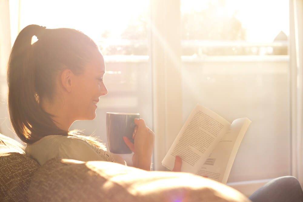 woman reading on couch with sun coming in window