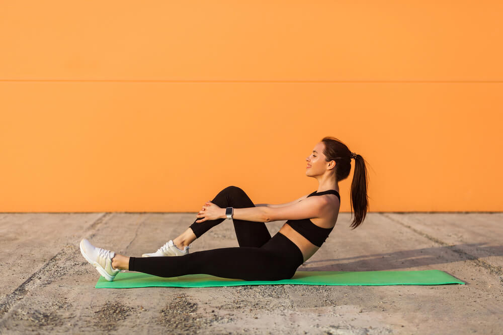 Woman working out outside near an orange wall