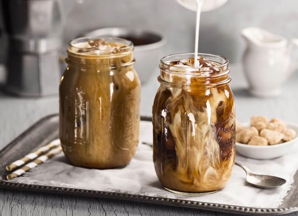 milk being poured into iced coffee