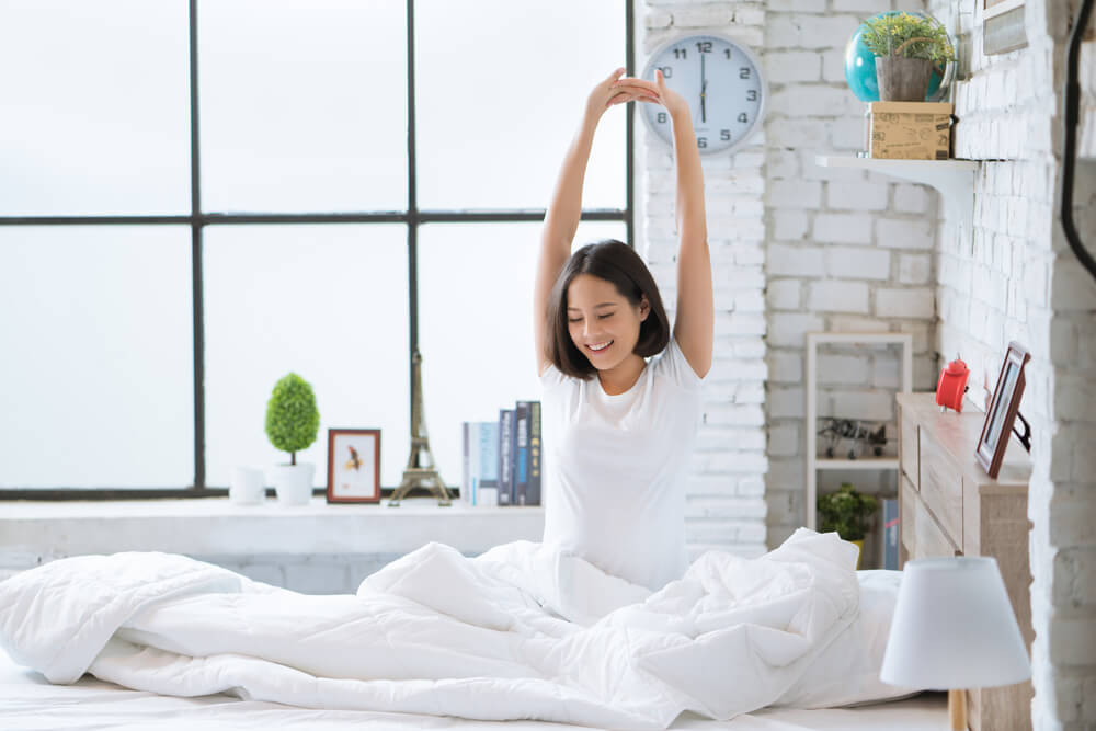 Woman waking up and stretching in bed