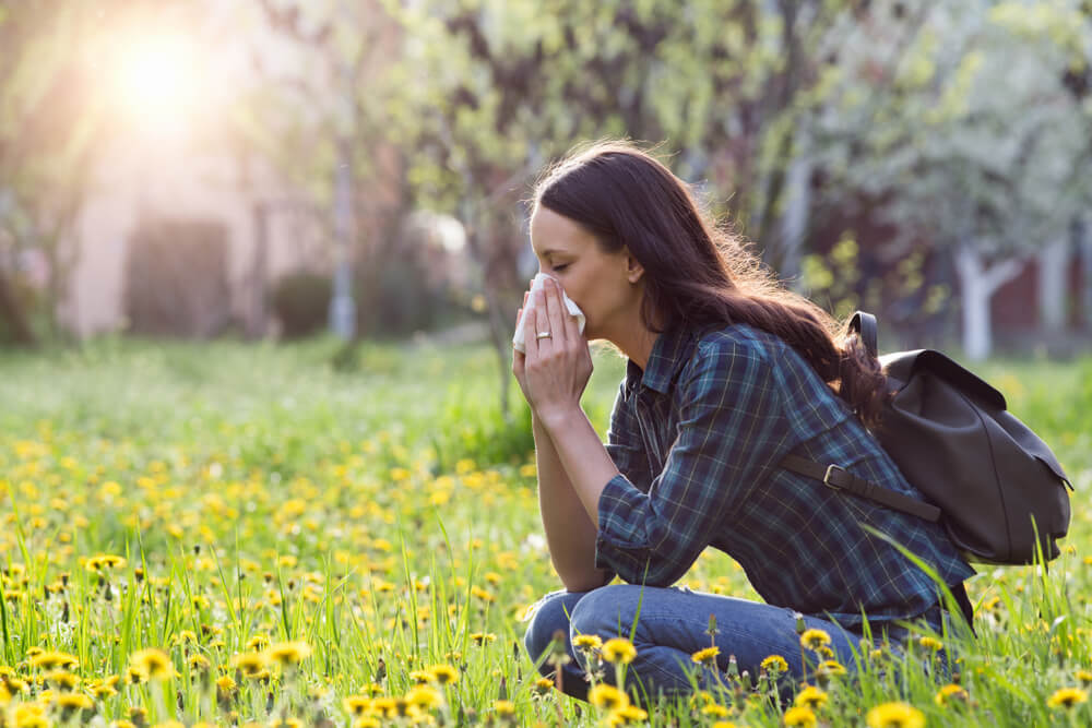 young woman blowing her nose outside